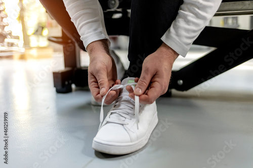Cropped shot of an unrecognizable sportsman tying his shoelaces in a gym. Shot of an unrecognizable man tying his shoelaces in the middle of his exercise routine. Close up.