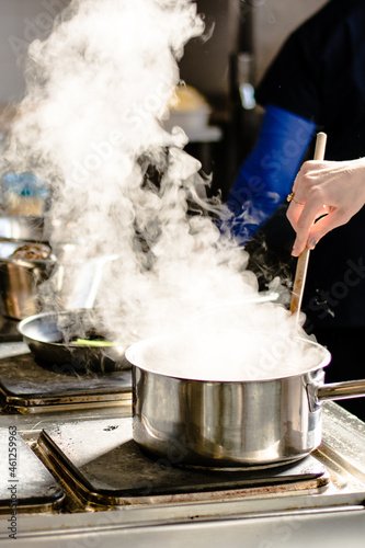 Chef cooking soup and water evaporating from a pot at a restaurant kitchen