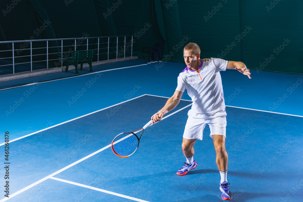 Full-length portrait of professional tenis player, man training over indoor  tennis court background. Returning a ball Stock Photo | Adobe Stock
