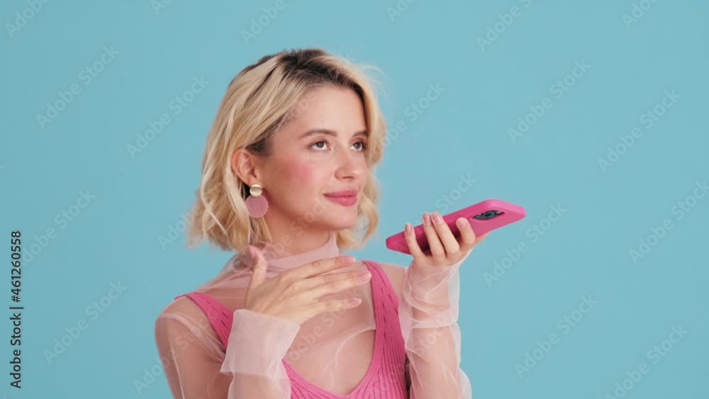 Close-up view of smiling woman recording a voice message on the phone in blue studio Close-up view of smiling woman recording a voice message on the phone in blue studio