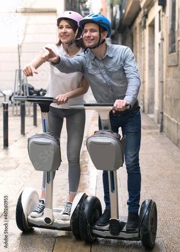 young couple guy and girl walking on segway in streets of european city photo