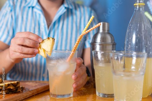 Man decorate the cocktail with a pineapple wedge at home for party