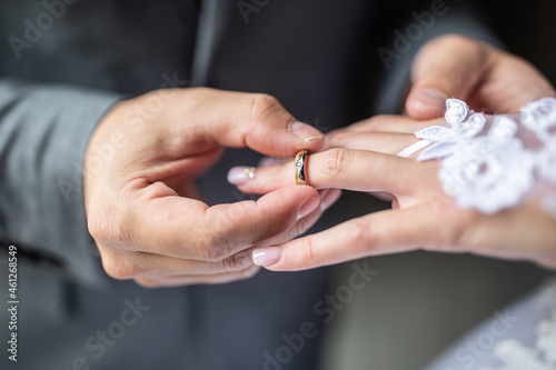Groom putting the wedding ring on bride finger close up.