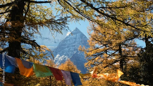 Sacred Xiannairi mountain with colorful prayer flags flying in autumn forest