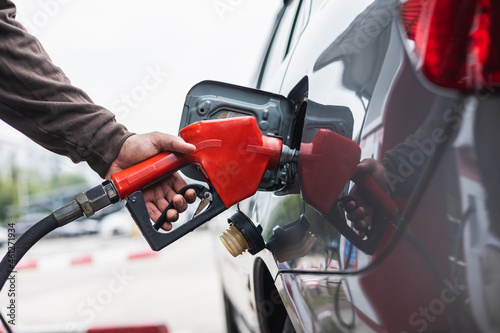 Bilde på lerret A gas station worker holds a fuel dispenser to fill the car with fuel