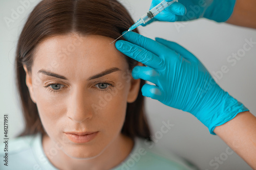 A dark-haired mid aged woman having a beaty injections procedure photo