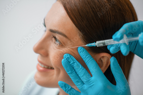 A dark-haired mid aged woman having a beaty injections procedure