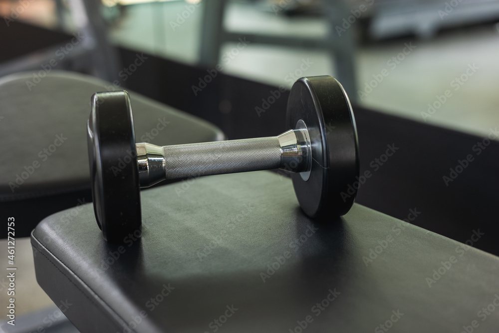 Dumbbell on the bench in modern indoor gym background. Fitness sport club with heavy weight training equipment for Muscular. Dumbbell on the bench in modern indoor gym background. Fitness sport club with heavy weight training equipment for Muscular.