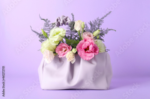 Stylish women's bag with beautiful flowers on violet background photo