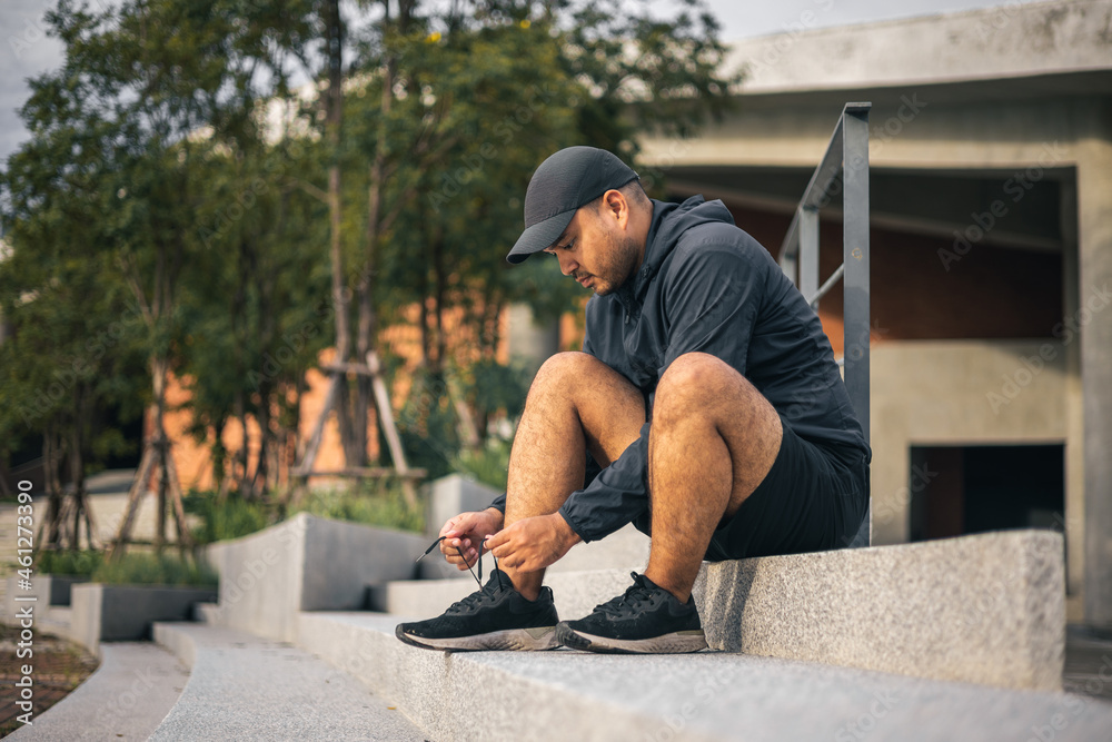 Runners tie their shoelaces prepared to run outdoors. Young asian man wearing sportswear running outdoor.Training athlete work out at outdoor concept.
