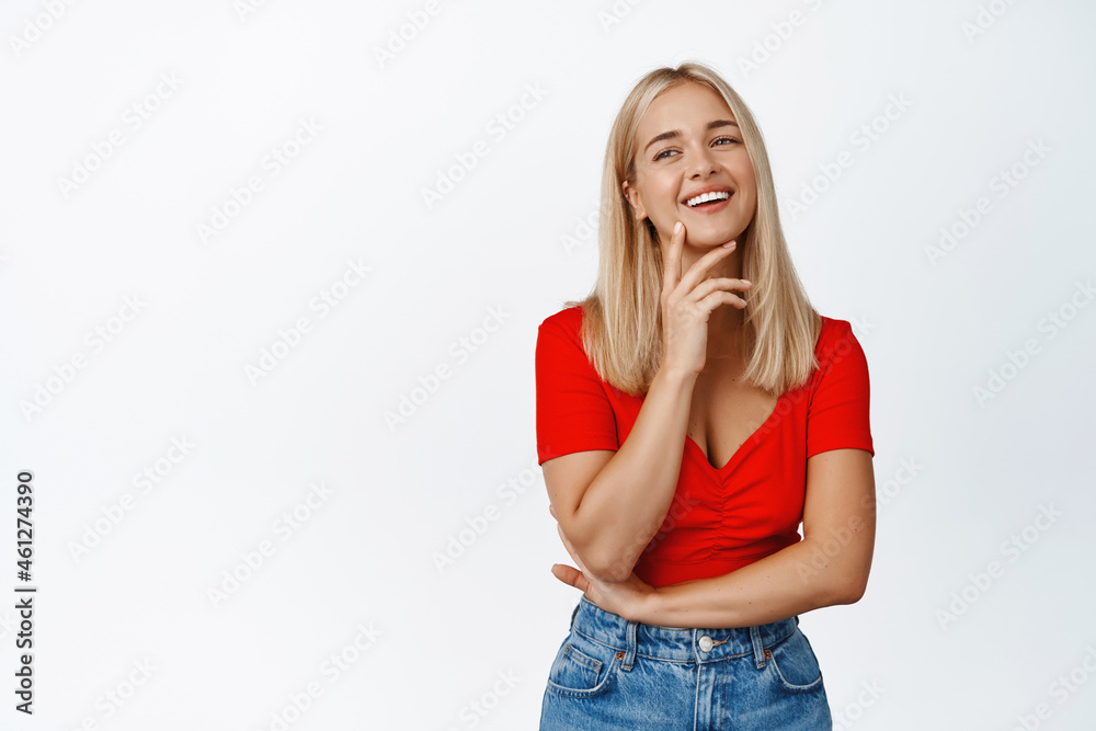 Beautiful blond woman laughing, smiling and looking happy, standing in stylish clothes against white background Beautiful blond woman laughing, smiling and looking happy, standing in stylish clothes against white background
