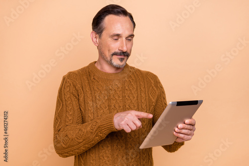Photo of think brunet man type tablet wear knitwear sweater isolated on beige color background