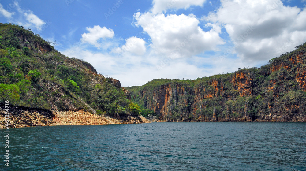 Rocky walls, with vegetation on top, of the canyons of the huge lake of the Furnas dam, blue sky with clouds, Capitolio, Minas Gerais, Brazil