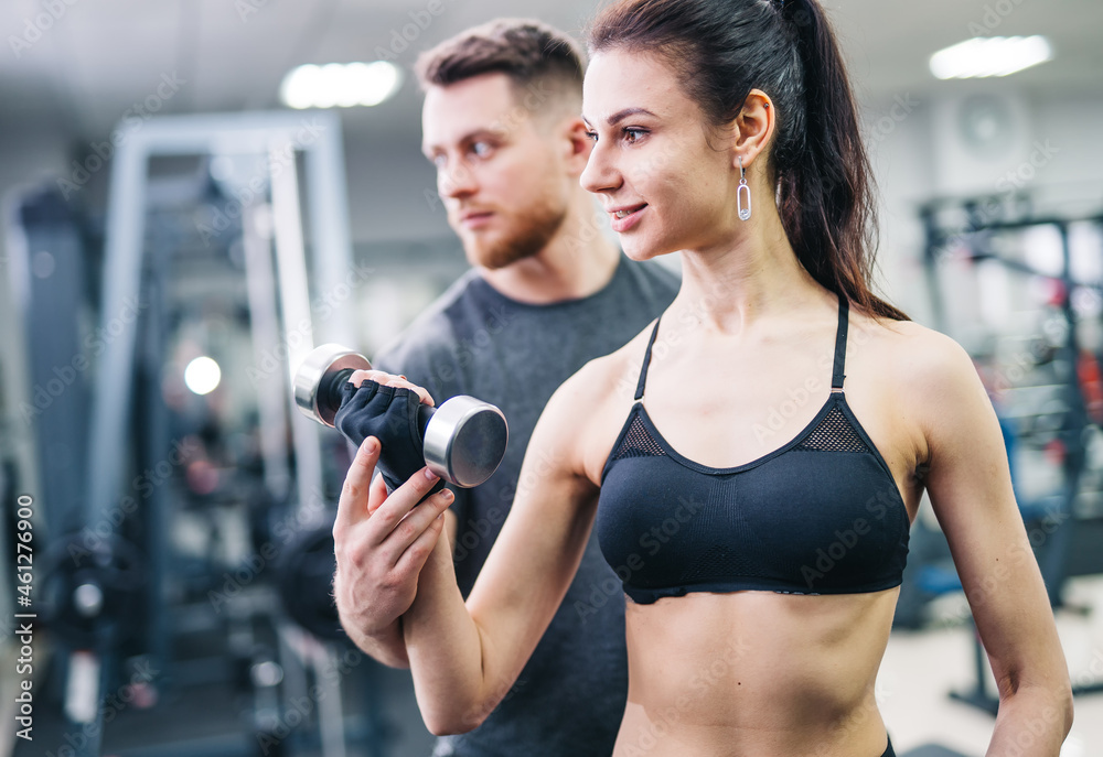 Fit woman working out with trainer at the gym. Athlete and beauty doing workout. Health life sport concept Fit woman working out with trainer at the gym. Athlete and beauty doing workout. Health life sport concept