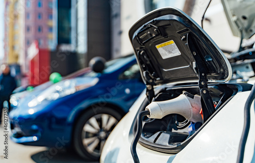 Close up of the hybrid car electric charger station with power supply plugged into an electric car being charged. Stock photo