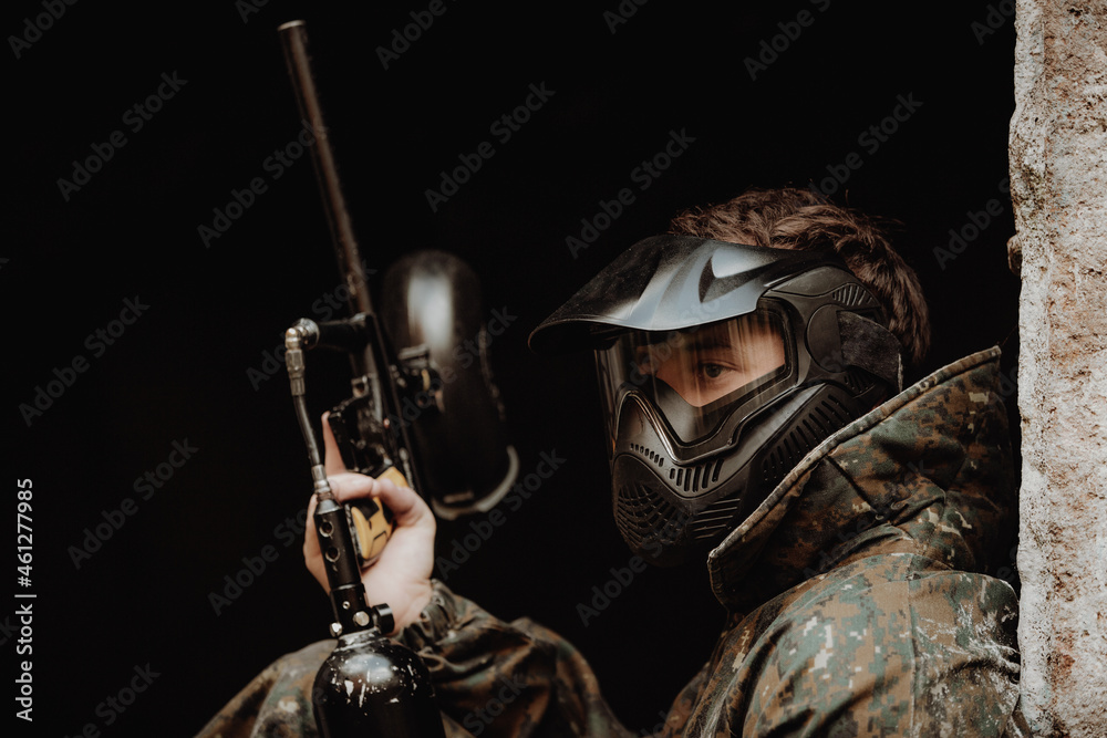 Portrait of young man with protective mask, paintball gun and camouflage wear, ready for an action paintball game Portrait of young man with protective mask, paintball gun and camouflage wear, ready for an action paintball game
