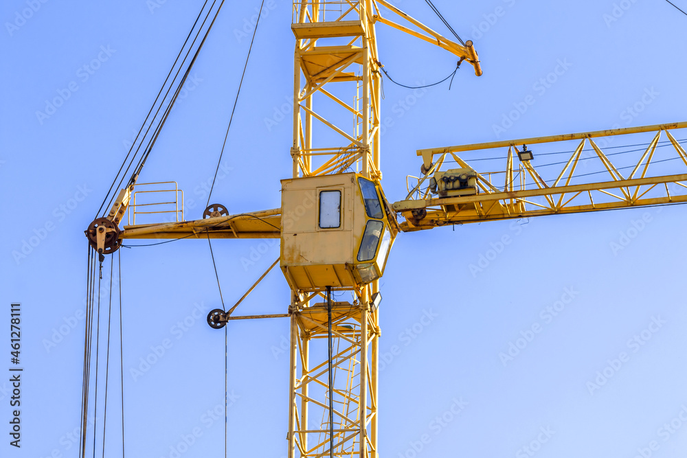 Yellow construction crane with cabin close-up against blue sky background. Concept of lifting of cargo, construction machinery and modern technology photo Yellow construction crane with cabin close-up against blue sky background. Concept of lifting of cargo, construction machinery and modern technology photo