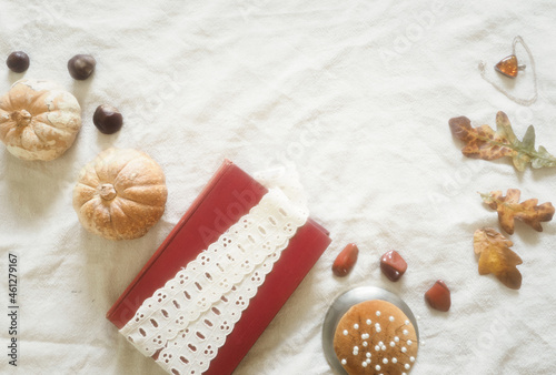 Light academia autumnal theme pin cushion, lace, book, and pumpkins, with ivory dressmaking pins.  Arranged on a linen and lace flat lay