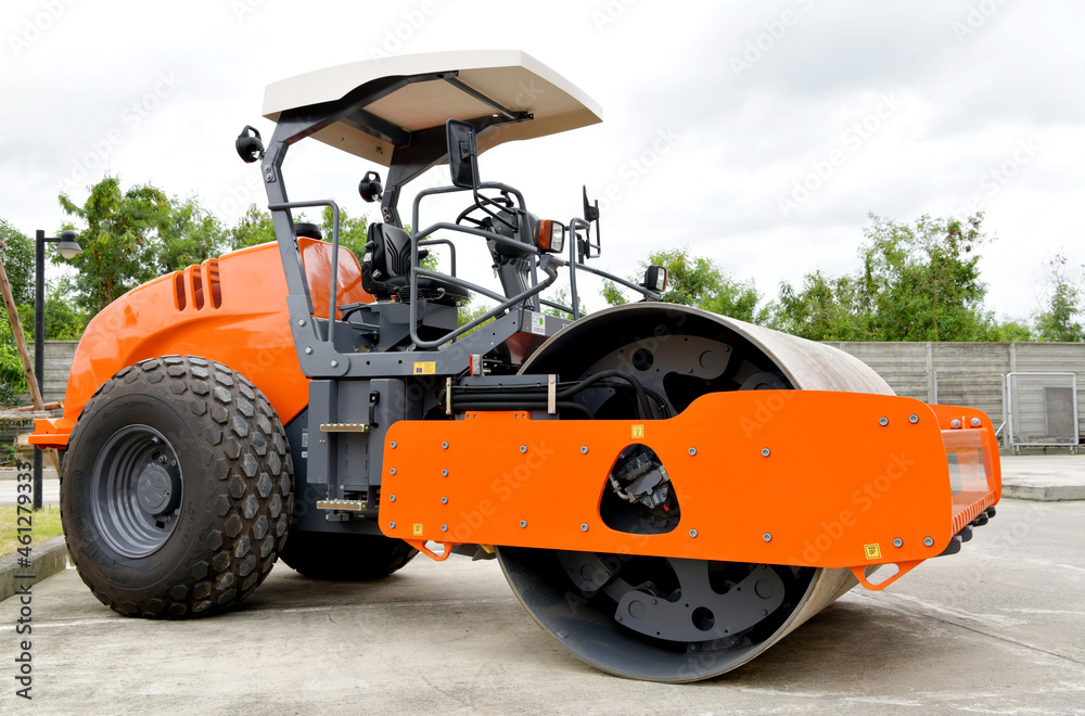 An orange road roller is parked in the company.