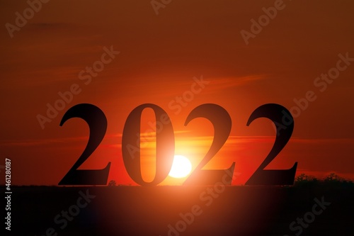 Happy New year 2022 with large silhouette letters on the mountain with sunset light,