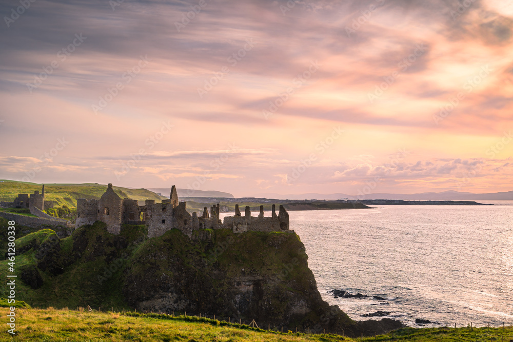Dramatic sky over ruins of Dunluce Castle, perched on the edge of cliff, Bushmills, Northern Ireland. Filming location of popular TV show Game of Thrones