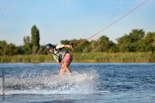 Teenage boy wakeboarding on river. Extreme water sport © New Africa