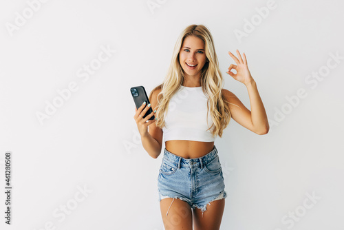 Young beautiful woman having conversation talking on the smartphone doing ok sign with fingers, excellent symbol