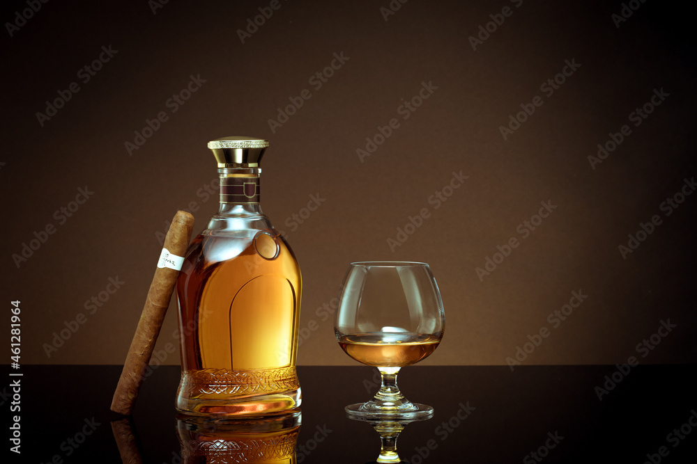 close up view of cigar, bottle of cognac and a glass aside on color back. close up view of cigar, bottle of cognac and a glass aside on color back.