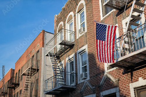 American Flag hanging from a Fire Escape along a Row of Old Brick Apartment Buildings in Astoria Queens New York