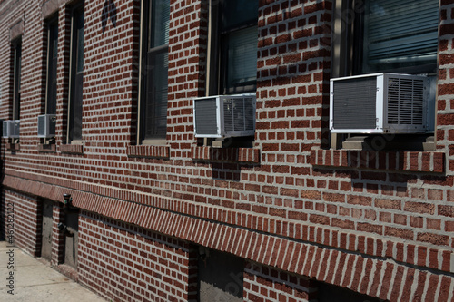Row of Window Air Conditioners Outside an Old Brick Apartment Building in Astoria Queens New York