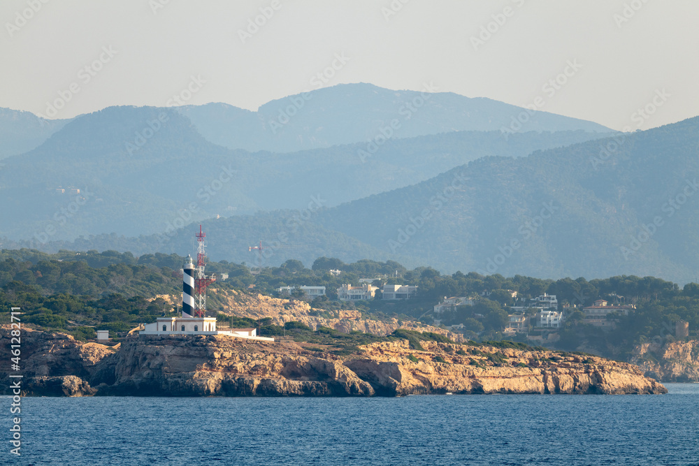 The lighthouse of Cala Figuera on the southern tip of the Spanish Mediterranean island of Mallorca seen from the sea. The mountains can be seen in the background.