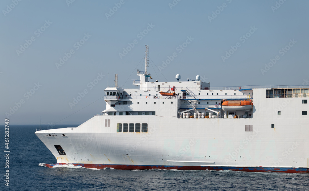 A white car ferry is on its way between the islands of the Balearic Islands in the Mediterranean. Lifeboats and life rafts can be seen on the side. Above are the radar and antennas.