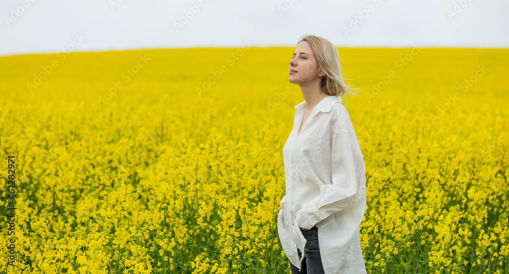Beautiful blonde in white shirt on yellow rapeseed field Beautiful blonde in white shirt on yellow rapeseed field