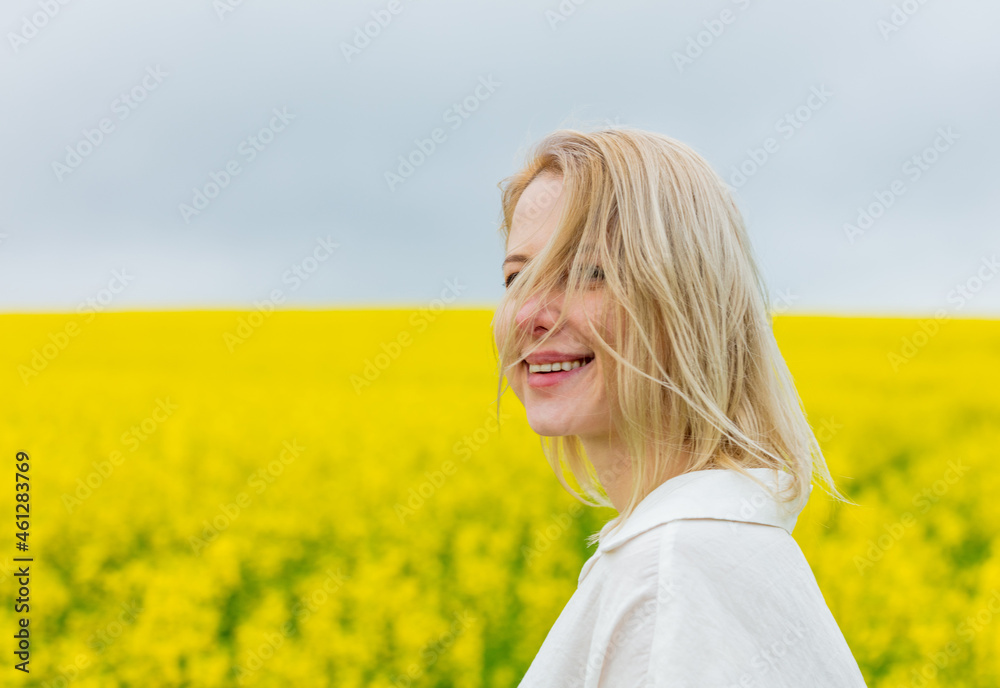 Beautiful blonde in white shirt on yellow rapeseed field Beautiful blonde in white shirt on yellow rapeseed field