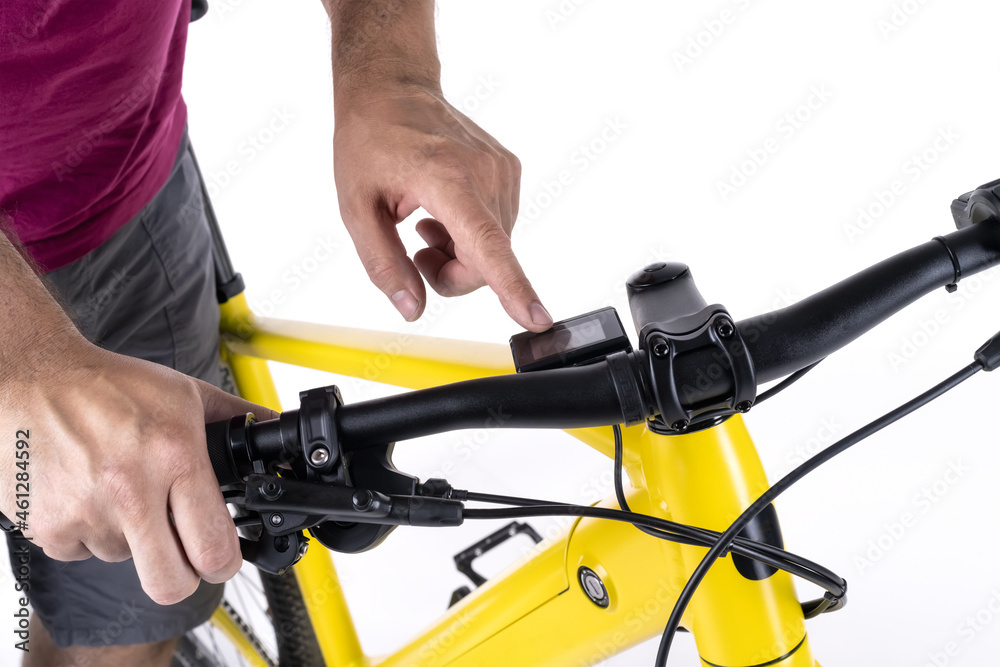 Unrecognizable male cyclist holding the handlebars of a bicycle, operating the digital control of the electric motor. Unrecognizable male cyclist holding the handlebars of a bicycle, operating the digital control of the electric motor.