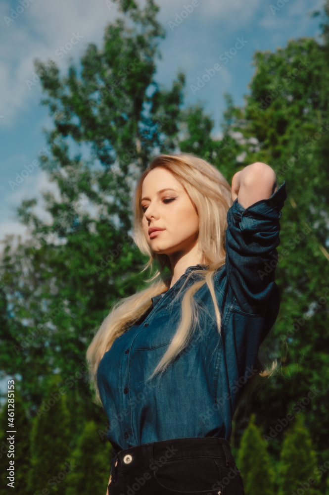 Beautiful blonde in demin shirt with trees on background in outdoor