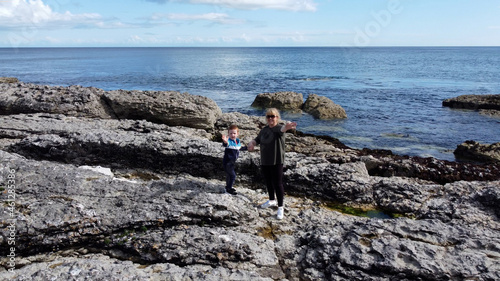 Aerial photo of Woman and child standing Rocks Mountains and Sea on Beautiful Scenery the North Coast of Ireland photo
