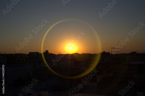 Fotografia di un tramonto con alone circolare riflesso.