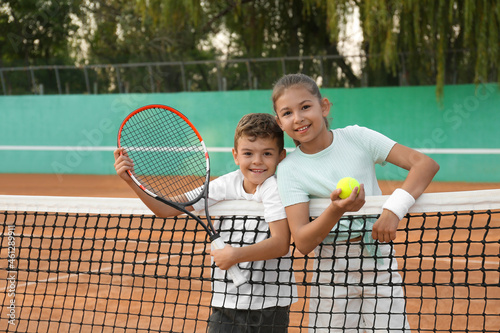 Happy children with tennis racket and ball on court outdoors © New Africa