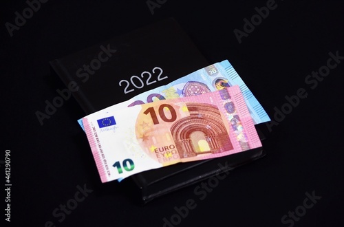 black notepad calendar 2022 and euro bills on black background