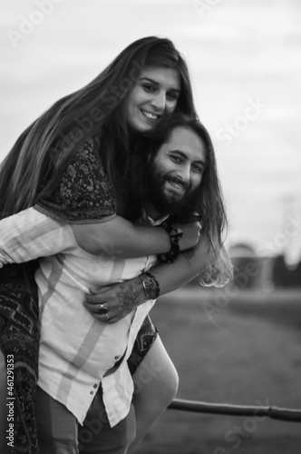 Black and white portrait of a young couple  bearded man carries on his back the Woman with long hair  and both smile