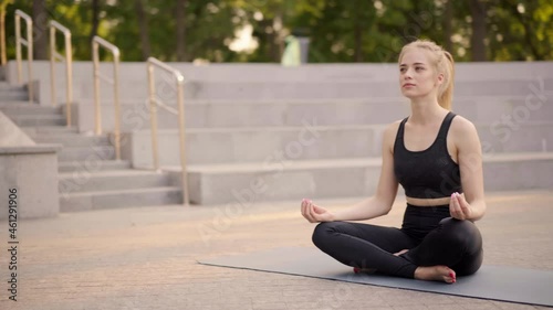 Yoga and Meditation in Modern City Caucasian Woman Relax Lotus Position Sitting Yoga Mat Outdoors Summer Park on Concrete floor Young Adult Fit Female Relaxing after Yoga Practice Workout Siddhasana photo