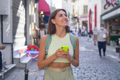 Young woman with mobile phone travels through the streets of Istanbul in a good mood enjoying the beauty of the city