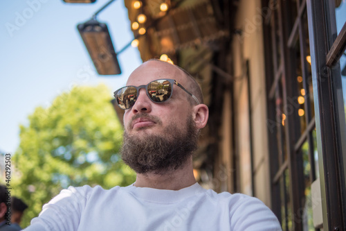 Handsome French bearded man with fashionable sunglasses sitting on a cafe terrace in Paris photo