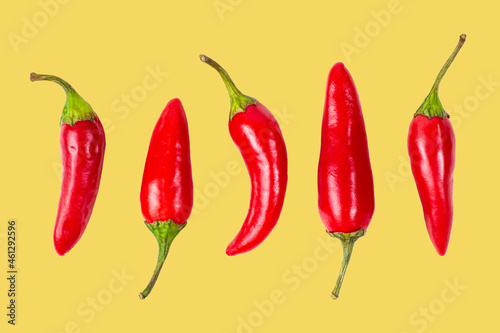 Photos Set of red hot chili peppers on yellow isolated, closeup.