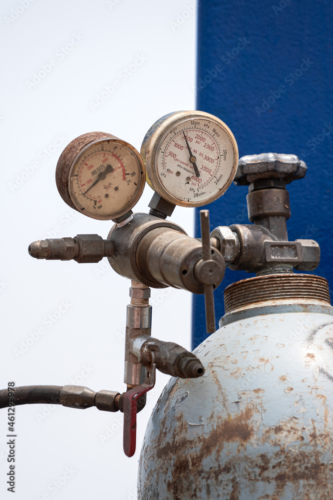 Pressure gauge indicator and regulator valve on the gas cylinder tank. Industrial equipment object photo. Close-up and selective focus.