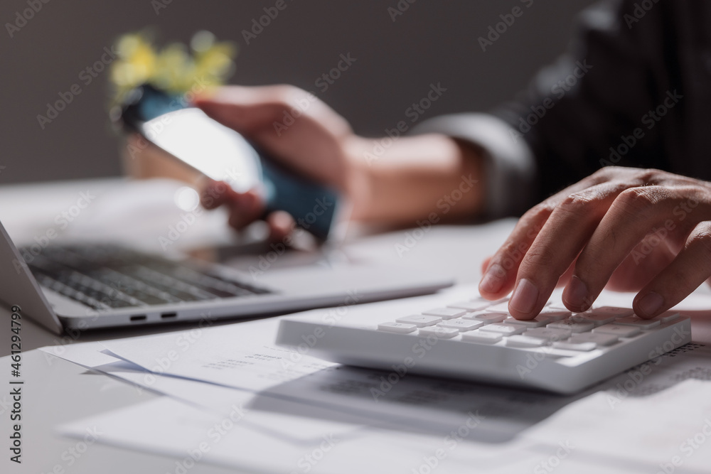 A young man was using a calculator to calculate his income and expenses. In his hand were smartphone to pay off a lot of debt. A young man was using a calculator to calculate his income and expenses. In his hand were smartphone to pay off a lot of debt.