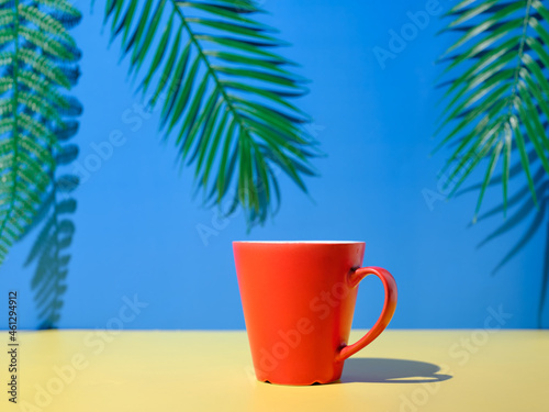 Red cup on yellow table and blue background with plants