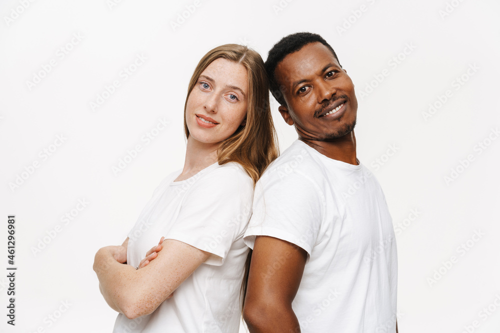 Obraz premium Multiracial couple wearing t-shirts smiling while standing back to back