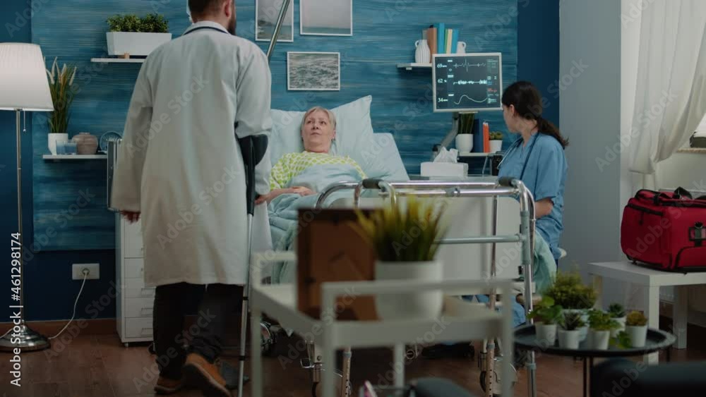 Nurse giving x ray scan to doctor for consultation with aged patient in hospital bed on nursing home facility. Medic looking at bones radiography for medical diagnosis and treatment Nurse giving x ray scan to doctor for consultation with aged patient in hospital bed on nursing home facility. Medic looking at bones radiography for medical diagnosis and treatment